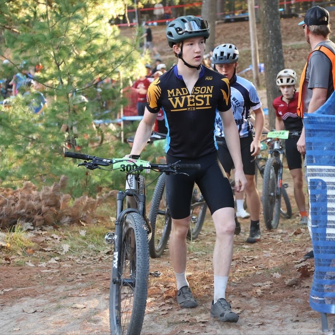 Caden Downing standing with his mountain bike at a race